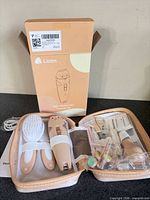 Opened storage case showing nail trimmer, attachments, brush, nail clippers, cable, instruction leaflet, and retail box