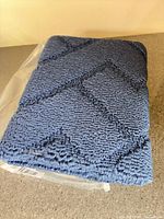 Folded navy blue carpet mat in original packaging on countertop