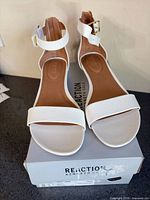 Top view of white Kenneth Cole Reaction ankle-strap sandals on box