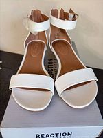 Top view of both white ankle-strap sandals on box