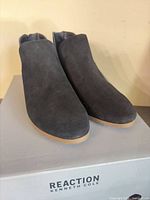 Pair of black suede Kenneth Cole Reaction ankle boots on box