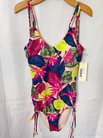 Front view of floral one-piece bathing suit showing print, straps, side ties and tag