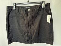 Front view of black skort showing pockets, button, tag attached