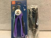 Front of packaged purple Bonve Pets nail clipper next to separate black clipper in sleeve