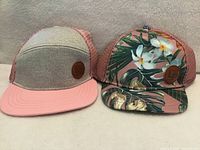 Front view of both hats showing designs and logo patches
