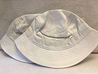 Two white bucket sun hats side by side, showing full shape and color