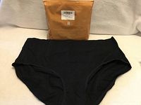 Front view of one black brief and sealed package