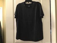 Front view of black short-sleeve top on hanger