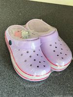 Top view of sealed purple clogs showing ventilation holes, strap and included charms