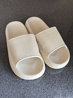 Angled view of pair of beige rubber slide sandals on countertop