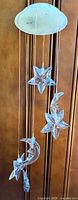 Full view of wind chime showing white top disc and hanging star and moon ornaments