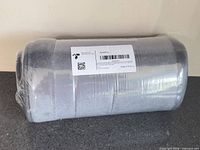 Rolled grey bath mat in shrink wrap showing label