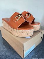 three-quarter view of sandals on box showing upper and buckle detail