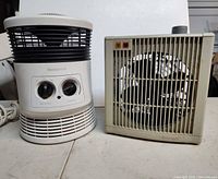 Honeywell cylindrical heater beside Duracraft rectangular heater, front view showing controls and grille