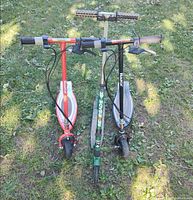 Front view of three kick scooters standing side by side on grass