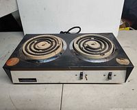 Front angled view showing both burners, switches, manufacturer plate, overall wear