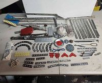 overview of all metal girders, plates, pulley, hardware, tools and instruction sheet comprising the Gilbert Erector set
