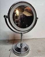 Front view of chrome tabletop vanity mirror on pedestal