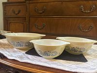 Three Pyrex Homestead bowls displayed side by side showing pattern and handles