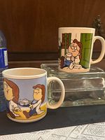 Both Tetley collector mugs showing different cartoon scenes