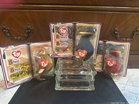 All three sealed Ty dinosaur figures displayed in front of dresser, packaging visible