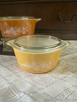 Golden-orange Pyrex Butterfly Gold 475-B casserole with lid in background; yellow 474-B casserole with lid in foreground.
