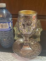 Goblet beside water bottle for scale, showing relief design and saucer