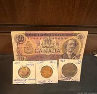Group shot of ten-dollar banknote and three coins in holders