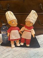 Front view of both dolls beside water bottle for scale
