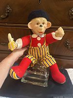 Front view of rubber faced stuffed monkey doll on glass stand