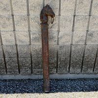 Full view of cast iron hitching post leaning against wall