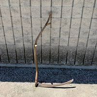 Full view of scythe showing wood snath and curved blade