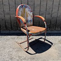 Full view of metal patio rocking chair showing structure and patina