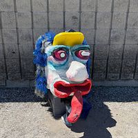 Full view of mask leaning against wall showing overall size and colours