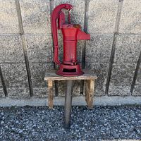 Front view of red cast iron water pump on stand
