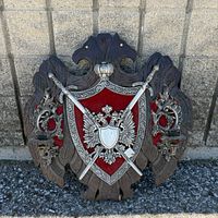 Full view of shield wall plaque with crossed swords, crest, and candle sconces