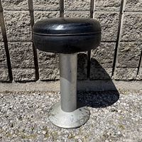Full view of stool showing leather seat, metal pedestal and base