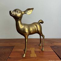 full view of brass deer standing on wooden surface