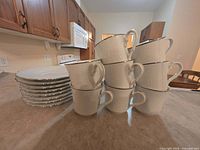 Stack of eight white saucers alongside pyramid stack of eight matching teacups