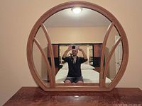 Front view of circular wood-framed mirror showing mullion design
