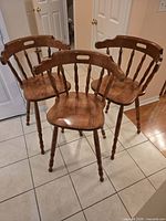 Front view of three matching wooden bar stools on tile floor