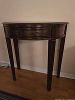 Front view showing semicircular top, drawers, legs