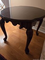 Full view of mahogany-stained end table showing glossy shaped top and cabriole legs