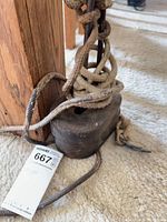 Overall view of cast iron weight with rope and tag