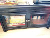 Front view of black TV stand showing glass doors and knobs