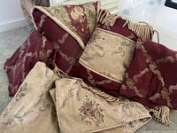 Assortment of burgundy and beige damask pillows and throw blanket