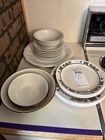 Stacks of Corelle dinnerware showing bowls, plates and patterned dishes