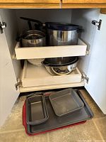 Cabinet showing pots, bowls, colander, baking pans