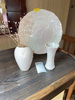 Plate, two vases and metal stand displayed together on table