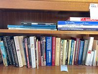 Shelf with two shark books, Scavullo photography, American Impressionism and first row of assorted hardcovers/paperbacks